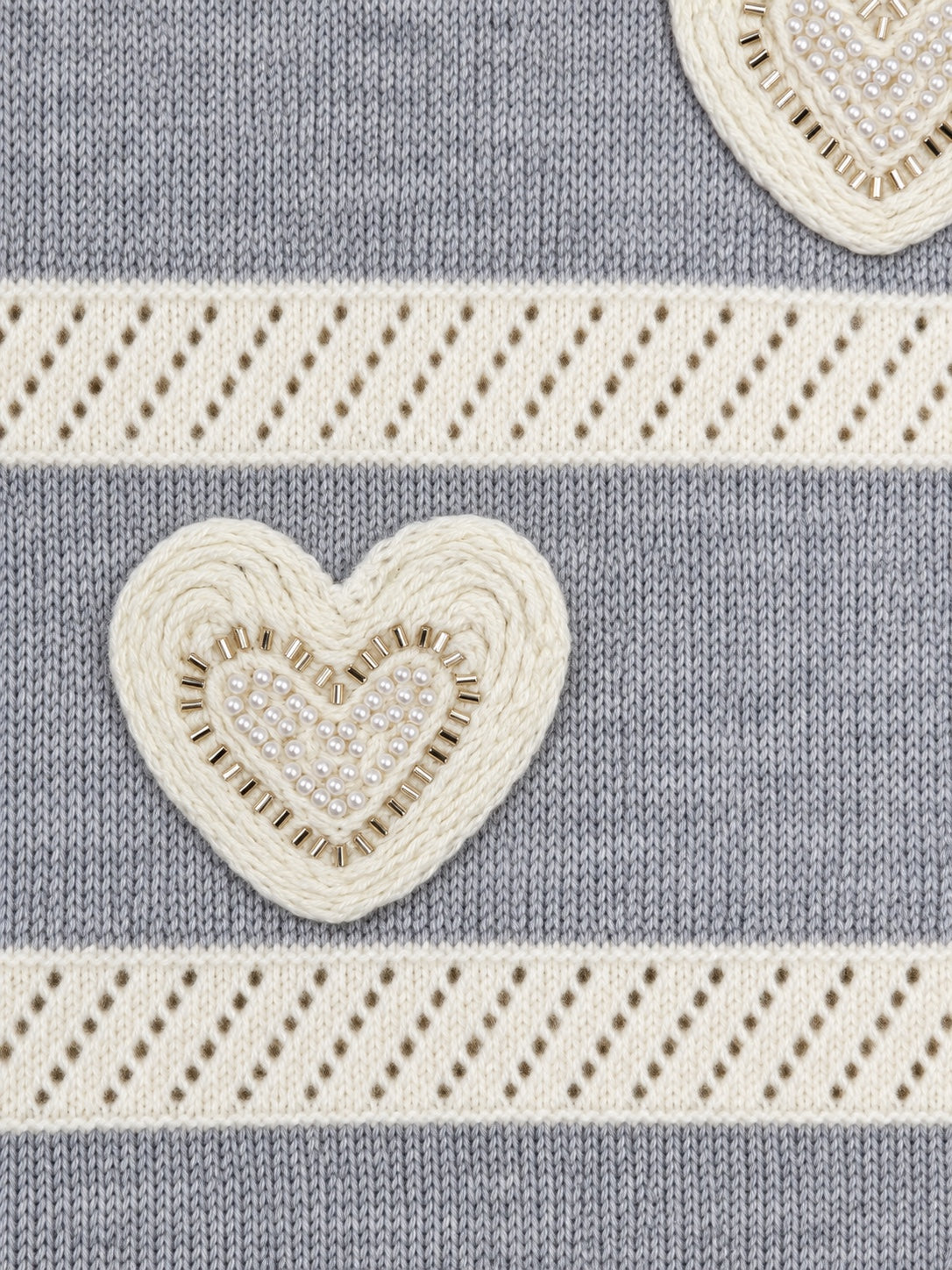Détail du cœur perlé du pull gris et écru